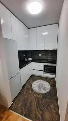a kitchen with white cabinets and a marble floor at Zlatni San apartman 1 in Banja Luka
