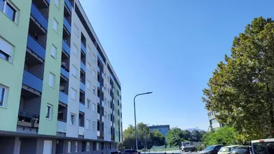 a tall building on a street with cars parked next to it at Zlatni San apartman 1 in Banja Luka