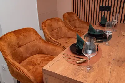 a wooden table with three chairs and wine glasses at Apartman Royal 1 in Doboj