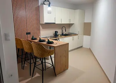 a kitchen with a bar with stools and a sink at Apartman Royal 1 in Doboj