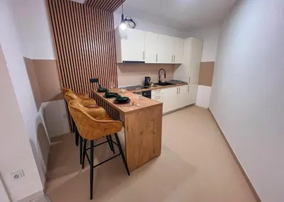 a small kitchen with a wooden island with stools at Apartman Royal 1 in Doboj