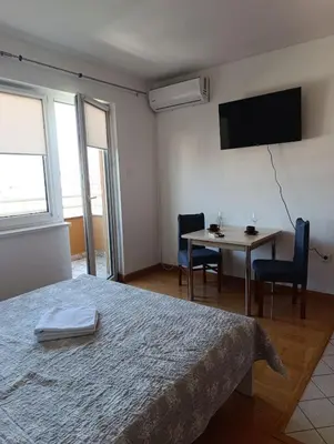 a bedroom with a bed and a table with chairs at Apartman AsHome in Banja Luka