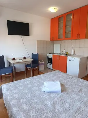 a kitchen with orange cabinets and a table with a towel on it at Apartman AsHome in Banja Luka
