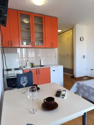 a kitchen with orange cabinets and a table with wine glasses at Apartman AsHome in Banja Luka