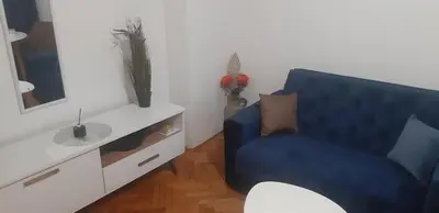 a living room with a blue chair and a mirror at Apartment CenterZeroZone in Banja Luka