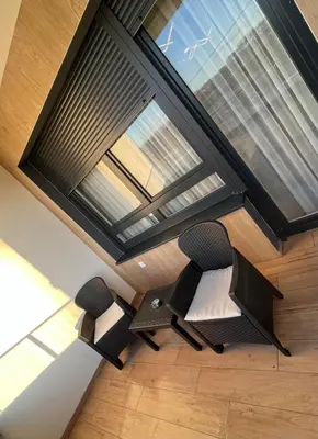 two chairs sitting in front of a large window at Stan na dan Libero Apartman in Banja Luka