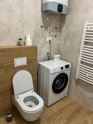 a bathroom with a toilet and a washing machine at Stan na dan Libero Apartman in Banja Luka