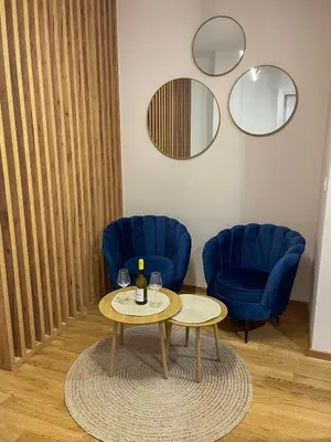 a living room with a table and two blue chairs at Stan na dan Libero Apartman in Banja Luka