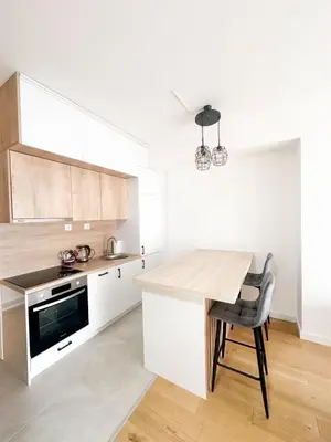 a kitchen with white cabinets and a table with a chair at KING - Apartment & SPA in Banja Luka