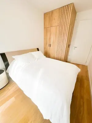 a bedroom with a white bed and a wooden cabinet at KING - Apartment & SPA in Banja Luka