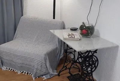 a table with a chair and a vase on it at Stepa apartman in Banja Luka