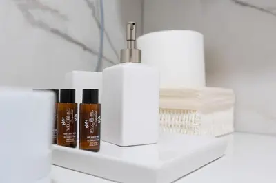 a bathroom shelf with three bottles ofodorizers and towels at Apartman Platinum in Banja Luka