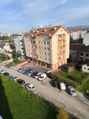 a large building with cars parked in a parking lot at Apartman Borik in Banja Luka
