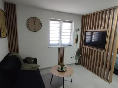 a living room with a clock on the wall and a table at Studio apartman Čolić - Kupres in Kupres