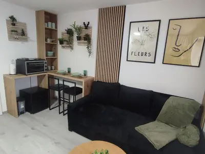 a living room with a black couch and a desk at Studio apartman Čolić - Kupres in Kupres