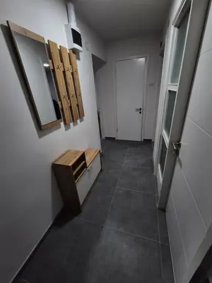 a hallway with a bathroom with a mirror and a door at Zevs Apartman in Prijedor
