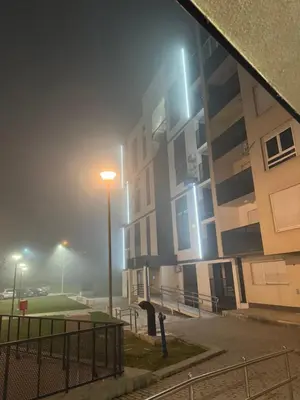 a foggy street with a building and a street light at Stay inn Tuzla in Tuzla