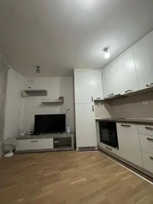 a kitchen with white cabinets and a flat screen tv at Stay inn Tuzla in Tuzla