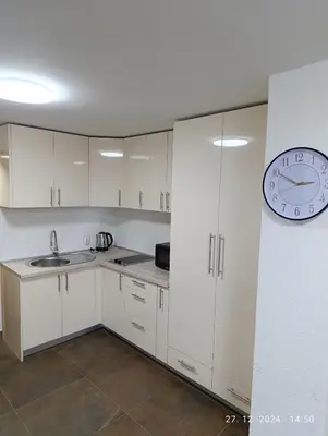 a kitchen with white cabinets and a clock on the wall at Stan Banja Luka in Banja Luka