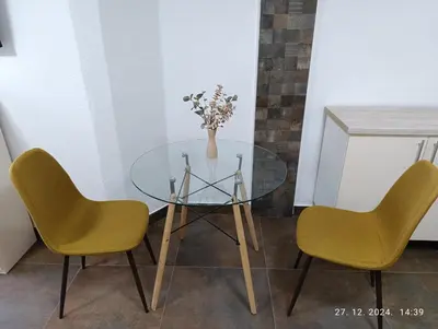 a glass table with two chairs and a vase with flowers at Stan Banja Luka in Banja Luka
