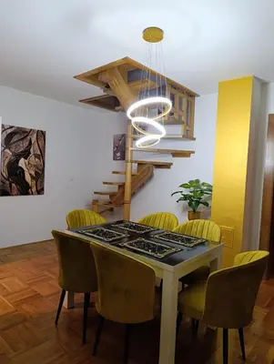 a dining room with a table with chairs and a chandelier at Apartman Gold&Black Banja Luka in Banja Luka