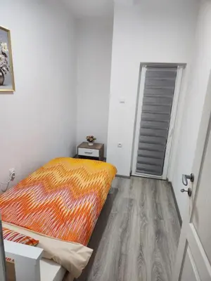 a bedroom with a bed with an orange blanket at Apartmani Una Lux in Spilja
