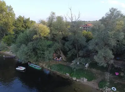 a group of people sitting on the shore of a river at Apartmani Una Lux in Spilja