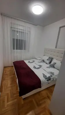 a bedroom with a bed and a window at Zlatni San apartman 2 in Banja Luka