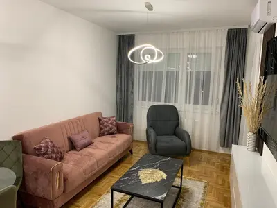 a living room with a brown couch and a chair at Zlatni San apartman 2 in Banja Luka