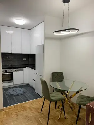 a kitchen with a glass table and green chairs at Zlatni San apartman 2 in Banja Luka