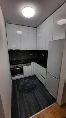 a kitchen with white cabinets and a black floor at Zlatni San apartman 2 in Banja Luka