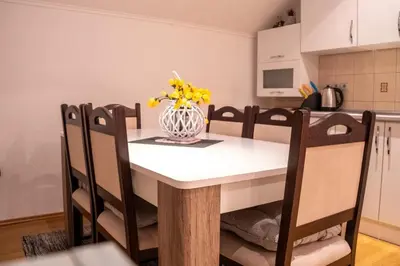 a dining room table with a vase of yellow flowers on it at Apartman KIKI in Kupres