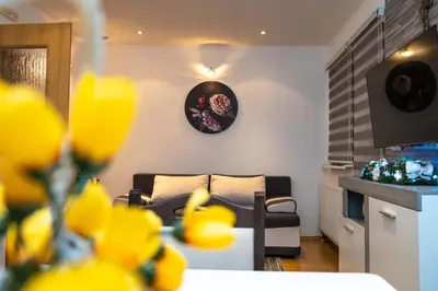 a living room with a couch and a table with yellow flowers at Apartman KIKI in Kupres