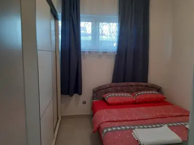 a small bedroom with a red bed and a window at Fest in Banja Luka