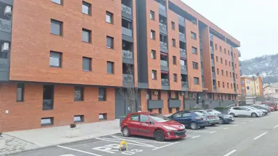 a red car parked in a parking lot in front of a brick building at Banja Luka Comfort - Wifi & Parking in Banja Luka