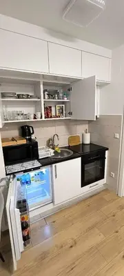 a kitchen with white cabinets and a black counter top at City apartman Modrica in Modriča