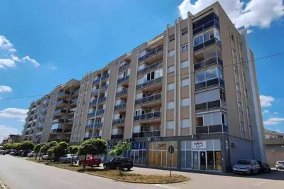 a large building with cars parked in a parking lot at City apartman Modrica in Modriča