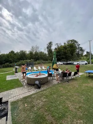 a group of people sitting around a hot tub in a park at Villa Uno Momento in Sreće