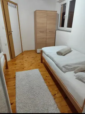 a bedroom with a white bed and a wooden floor at Kuća za odmor Kukavičko jezero in Kupres