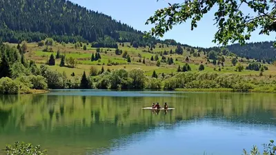 three people on a paddle board on a lake at Kuća za odmor Kukavičko jezero in Kupres