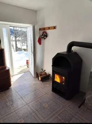 a fireplace in a living room with an open door at Kuća za odmor Kukavičko jezero in Kupres