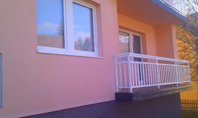a pink house with a balcony and a window at Apartman Kupres u centru grada in Kupres