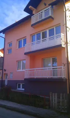 a pink and orange house with a balcony at Apartman Kupres u centru grada in Kupres