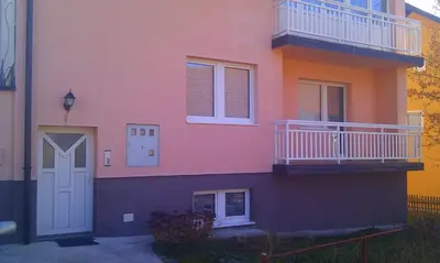 a pink house with a white door and balcony at Apartman Kupres u centru grada in Kupres