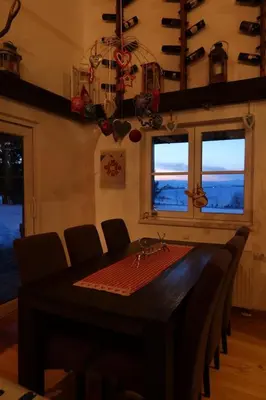 a dining room with a table and chairs and windows at Planinska kuća Ema in Kupres
