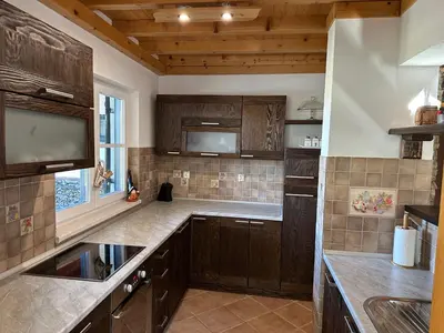 a large kitchen with wooden cabinets and a sink at Planinska kuća Ema in Kupres