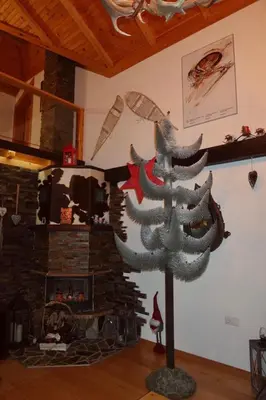 a christmas tree in a living room with a fireplace at Planinska kuća Ema in Kupres