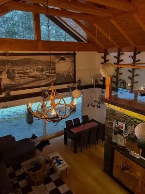 a living room with a fireplace and a chandelier at Planinska kuća Ema in Kupres