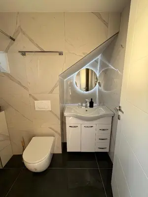 a white bathroom with a toilet and a sink at Kastel Apartmani in Banja Luka