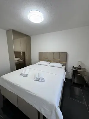 a bedroom with a large white bed with two shoes on it at Kastel Apartmani in Banja Luka